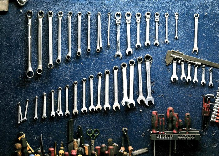 Neatly arranged wrenches and tools on a workshop wall, ideal for mechanics.